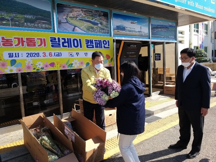 무안군 김산군수가 화훼농가돕기 릴레이캠페인에 참여, 꽃다발을 전달하고 있다.