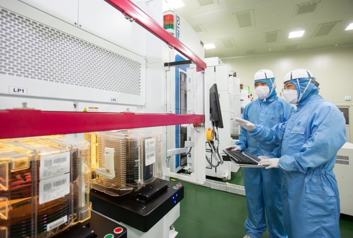 삼성전자 직원(오른쪽)과 이오테크닉스 직원이 양사가 공동 개발한 반도체 레이저 설비를 함께 살펴보고 있다.