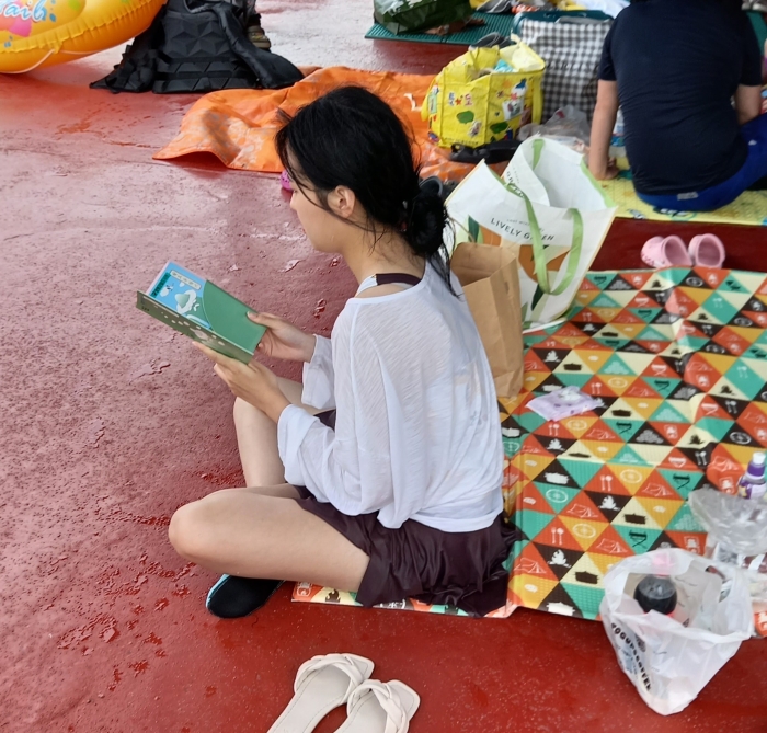 함평 엑스포공원 물놀이장에서 함평군이 이벤트로 나눠준 책을 읽고 있는 소녀의 모습