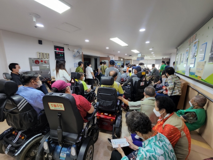 목포시장애인복지관 2022 한가위 어울한마당에 참석한 장애인들이 비좁은 행사장에 입장하지 못하고 복도에서 VCR을 보며 즐거운 시간을 보내고 있다.